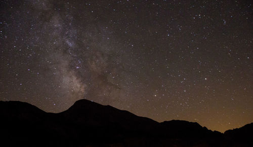 Low angle view of silhouette mountain against sky at night