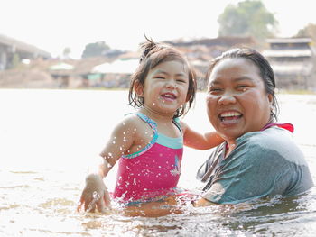 Portrait of smiling mother and daughter swimming in lake