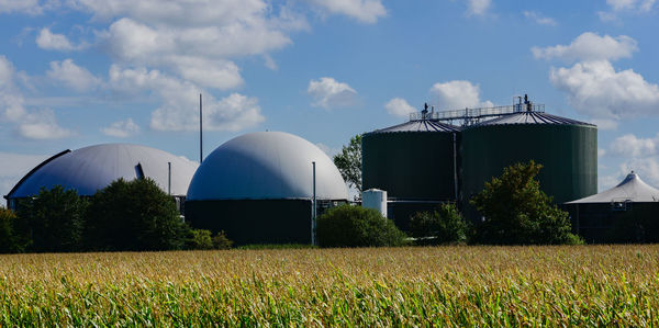 Industry on field against sky