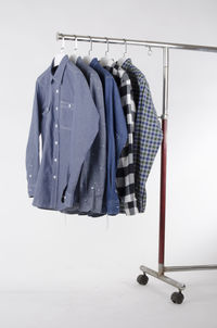 Shirts hanging on metallic rack against white background