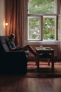 Woman using laptop while sitting on sofa at home