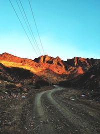 Road by mountain against clear blue sky