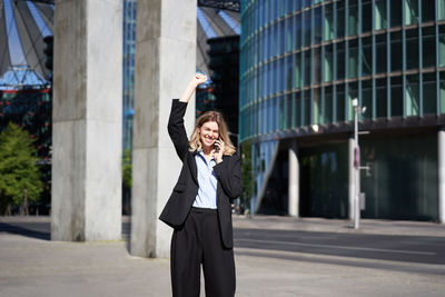 Portrait of young woman standing against building