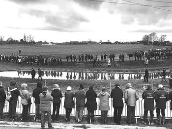 Group of people standing on field against sky