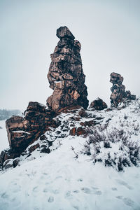 Rock formation on snow against sky