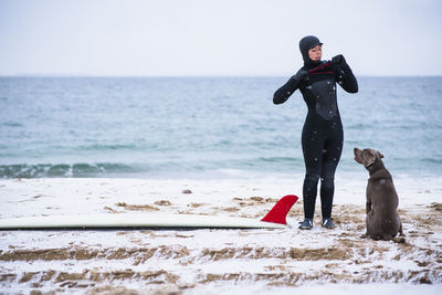 Young woman and dog going winter surfing in snow