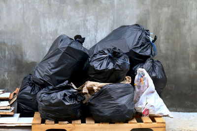 Rear view of man sitting on garbage against wall