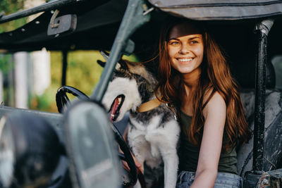 Portrait of young woman with dog in car
