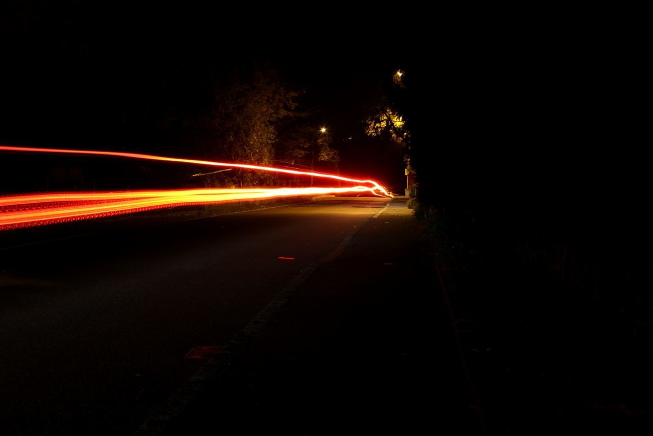 LIGHT TRAILS ON ROAD IN CITY AT NIGHT