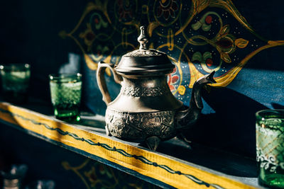 Ceramic and metal kettles with glasses small cups on colorful shelves in morocco