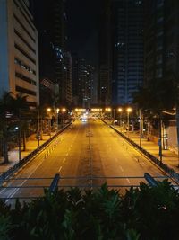 Illuminated street amidst buildings in city at night