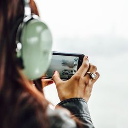 Midsection of woman using smart phone against sky