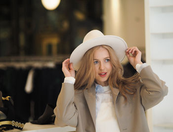 Beautiful woman wearing hat looking away at clothing store