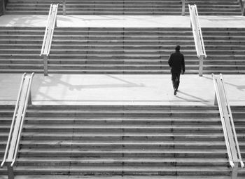 Man in black business clothing walking upstairs in a city