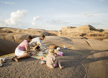 Family enjoying picnic on rock formation against sky