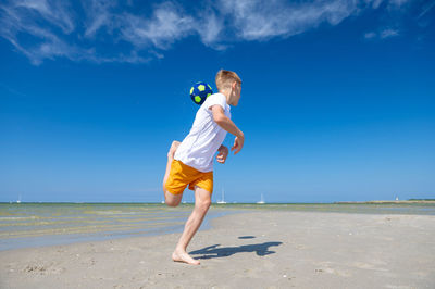 Full length of boy on shore at beach against sky