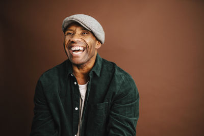 Mature man laughing against brown background in studio