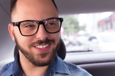 Close-up of smiling young man wearing eyeglasses in car