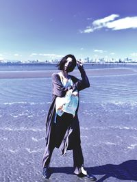 Full length of woman standing at beach against sky