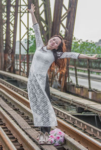 Portrait of smiling young woman standing at railroad station