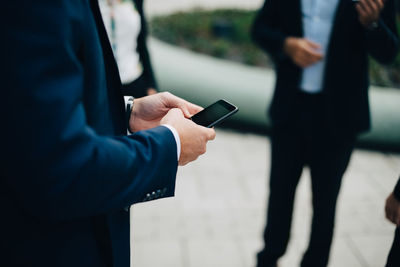 Midsection of man using mobile phone