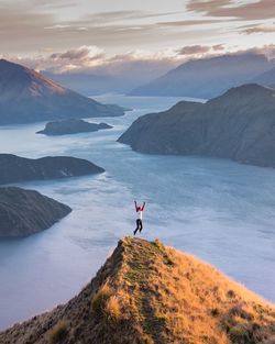 Person jumping on mountain at sunset