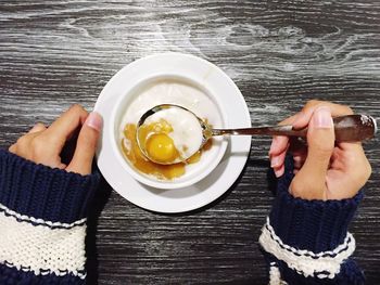Cropped woman hand with porridge in bowl on table