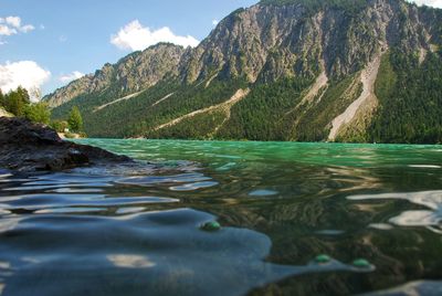 Scenic view of river by mountains against sky