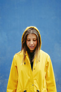 Young woman standing against blue wall