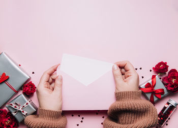 Cropped hand of woman holding gift against white background