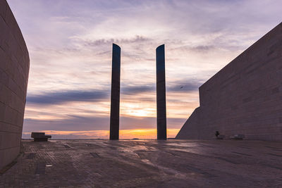 Scenic view of sea by buildings against sky during sunset