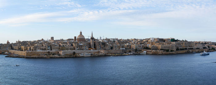 View of buildings by sea against sky in city