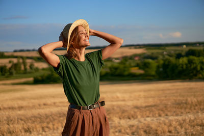 Smiling woman standing on land against sky