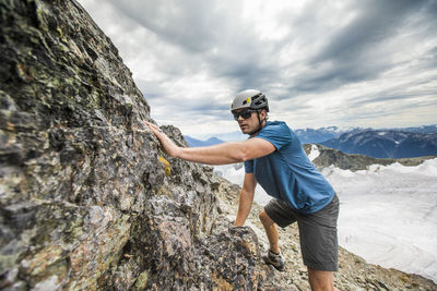 Side view of climber scrambling up toward mountain summit.