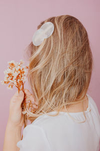 Rear view of woman with pink flower against white background