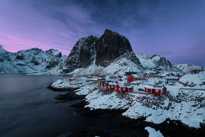 Houses in town by lake against snowcapped mountains