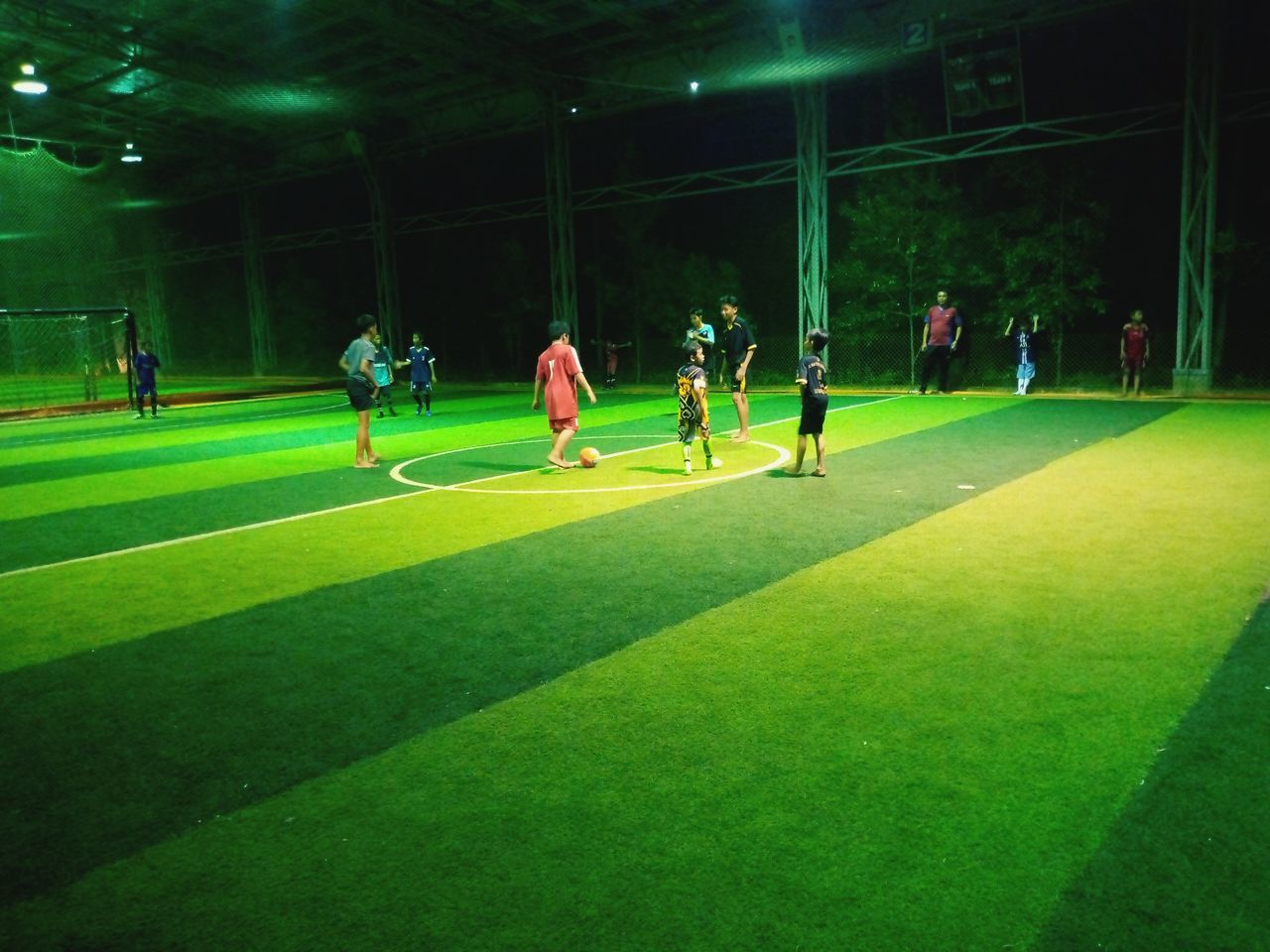 sports, green, group of people, grass, soccer, team sport, sport venue, soccer-specific stadium, stadium, men, athlete, soccer field, night, artificial turf, lawn, sports clothing, player, adult, teamwork, competition, cooperation, soccer player, leisure activity, full length, soccer uniform, group, sports team, kicking, medium group of people, lifestyles, crowd, sports equipment, nature, person, ball, togetherness, clothing, arena, motion, exercising, activity, illuminated, soccer ball