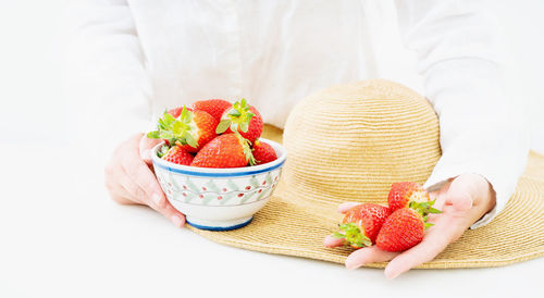 Midsection of woman holding strawberries in bowl
