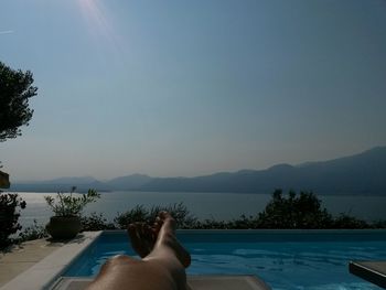 Low section of woman on lake against clear sky