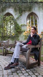 Full length of woman sitting on bench against building