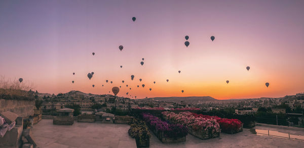 Hot air balloons flying over buildings in city during sunset