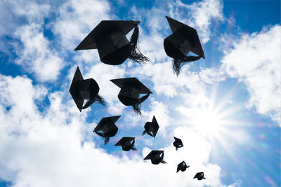 Low angle view of mortarboards flying against sky