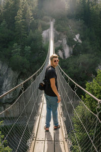 Portrait of man standing on footbridge in forest