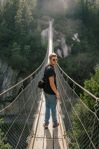 Woman standing on footbridge in forest