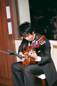 Man playing guitar while sitting on chair