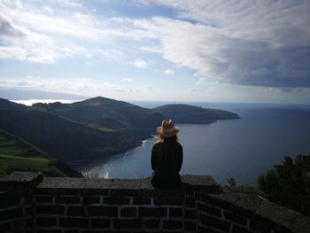 Rear view of woman on shore against sky