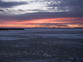 Scenic view of sea against cloudy sky at sunset