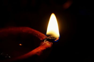 Close-up of illuminated light candle against black background