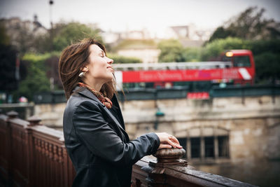 Brunette girl in a black jacket stands on the bridge