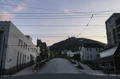 Road amidst buildings in city against sky